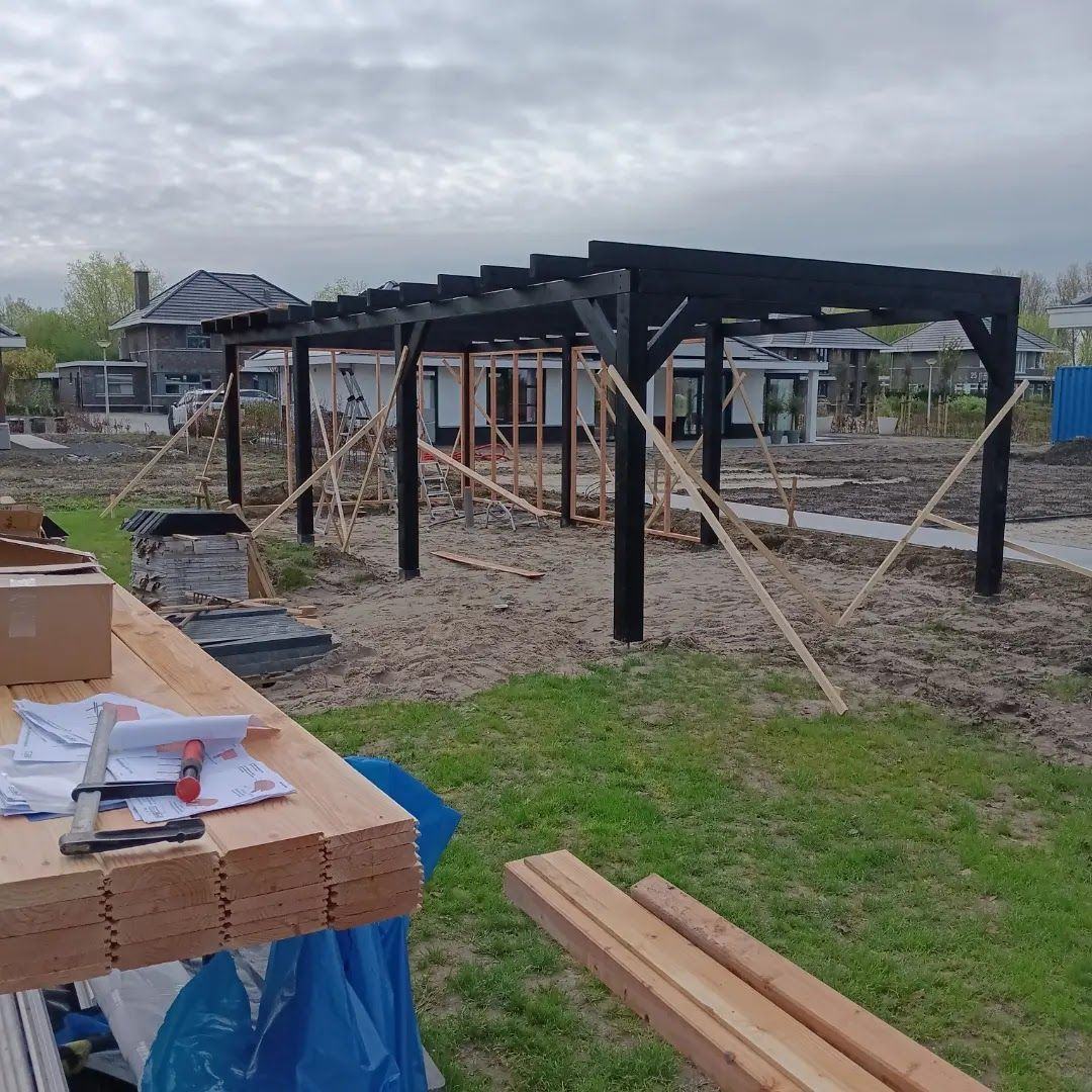 Zwarte pergola in aanbouw in een nieuwe tuin, planken op schragen